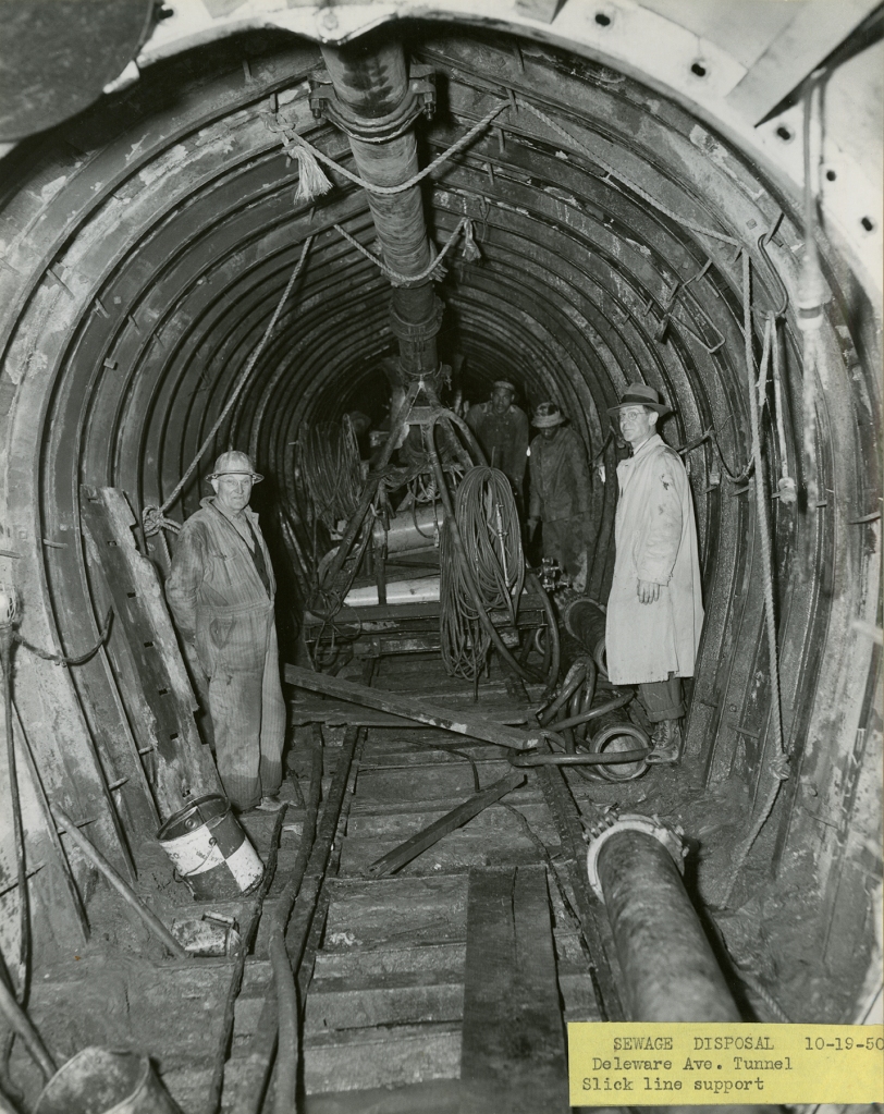 Men standing the tunnel with machinery. 